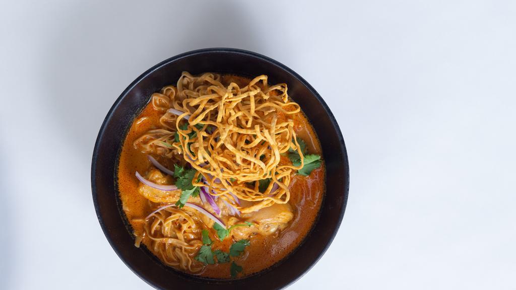 Curry Chicken Noodle (Khao Soi) · Egg noodles drenched in a creamy yellow coconut curry served with chicken thighs, green onion, red onion and cilantro.