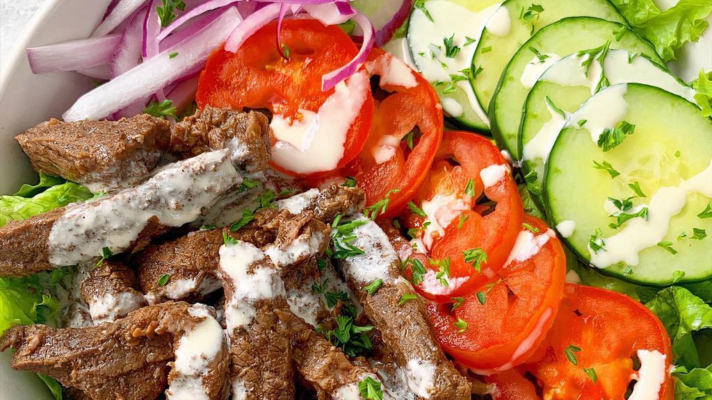 Beef Shawarma Salad · Our house salad topped with beef shawarma and garlic thomia sauce and a pita bread on the side