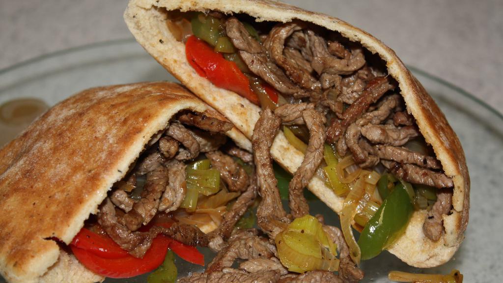 Beef Shawarma · Lightly seasoned beef strips with middle eastern spices served on warm pita bread with a spread of garlic thomia, Grilled peppers and Onions topped with Lettuce, Tomatoes and pickles