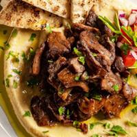 Hummus Beef Shawarma · Seasoned beef  shawarma strips grilled vegetables and onions layered over hummus and served ...