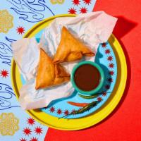 Lamb Samosas · Two samosas filled with lamb and wrapped in a light pastry.