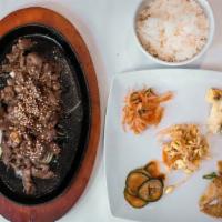 Korean Steak Bulgogi · Served with Rice and Bonchon on a hot plate with onion.