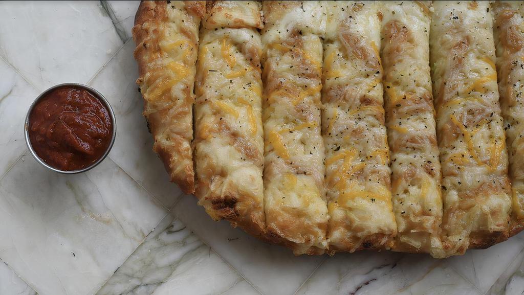 Vegan Cheesy Garlic Bread · Homemade roasted garlic purée and melty vegan mozzarella and cheddar cheese topped with parmesan, Italian herbs, and olive oil.
