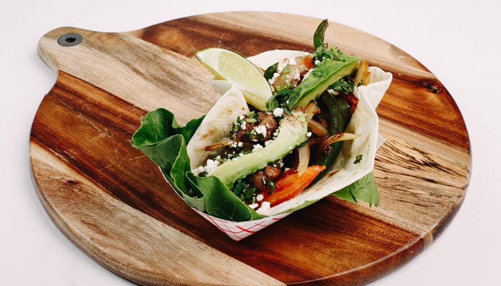 Steak Fajita Taco · Marinated steak served with grilled onions, peppers, tomatoes, avocado slices, cilantro, feta cheese and lime wedges