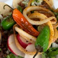 Tacos · Small tortillas, meat, onions, cilantro, grilled onions, lime, jalapenos, and radishes.