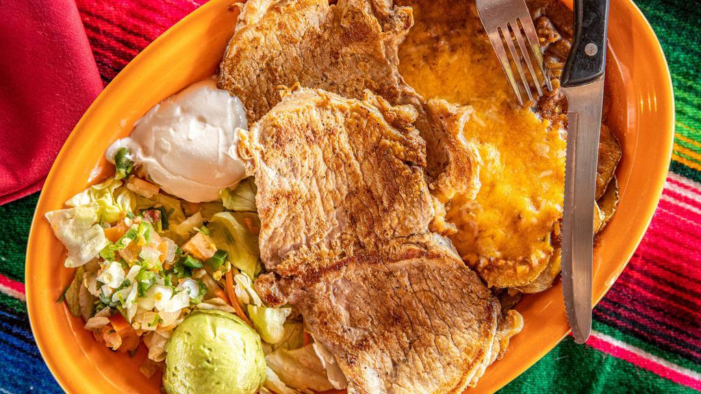Chuletas Rancheras · Two grilled boneless pork chops served with papas rancheras covered with cheese, served with refried beans, sour cream, pico de gallo and guacamole.