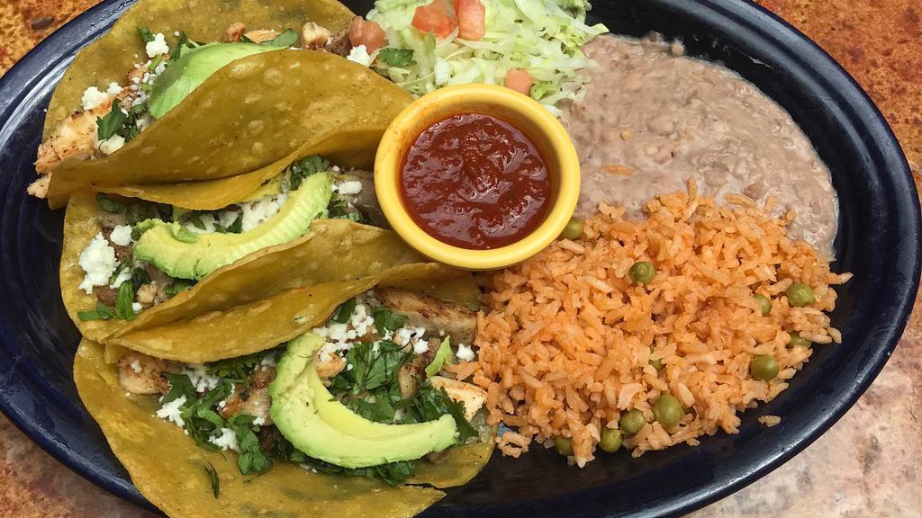 Fajita Tacos · Two soft corn tortillas filled with onions and tomatoes with your choice of grilled seasoned beef steak or chicken, topped with Mexican white cheese & a slice of avocado. Served with a side of Spanish rice, refried beans or black beans.