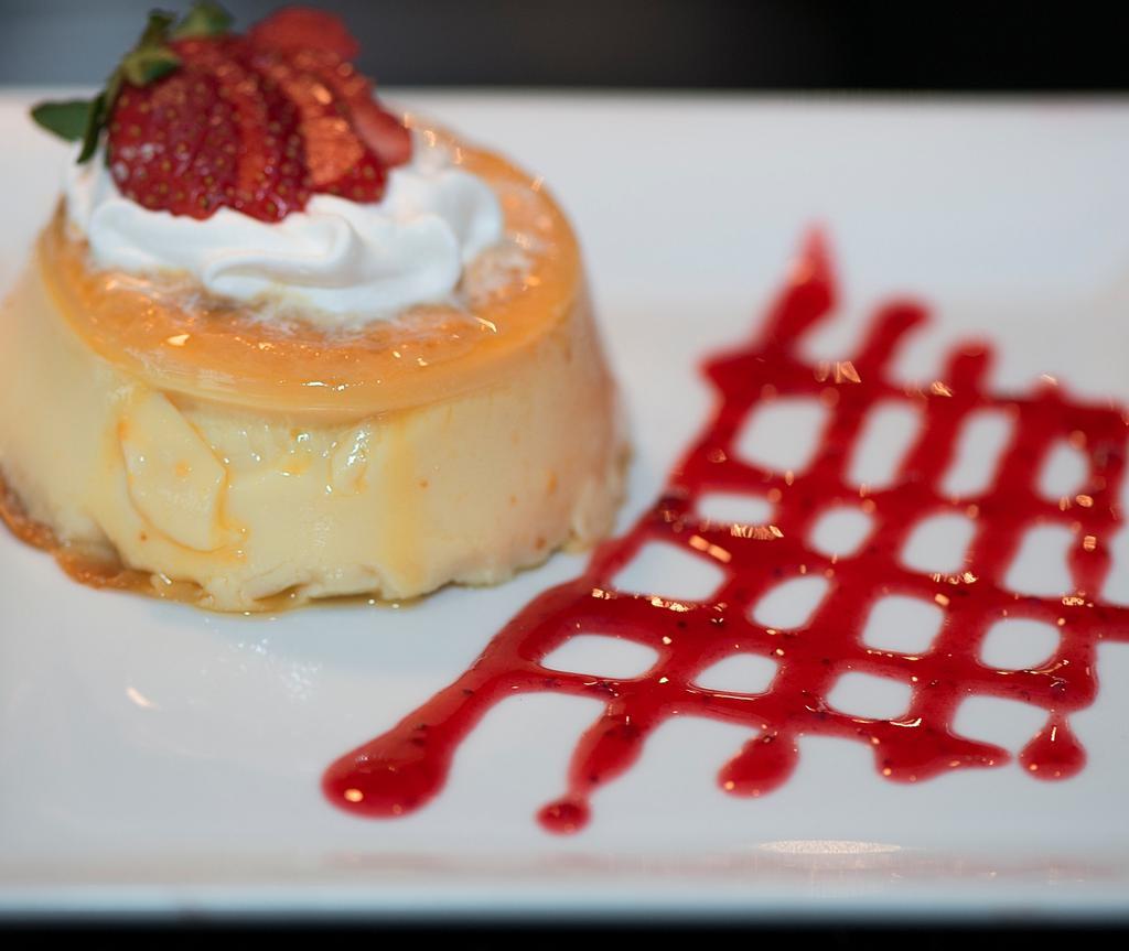 Flan Mexicano · A creamy rich vanilla custard topped with caramelized sugar whipped cream and strawberries.