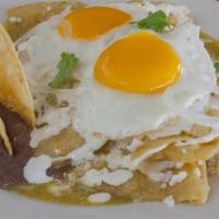 Chilaquiles · Tortilla chips cooked in green salsa, a side of grilled steak and two fried eggs; garnished ...