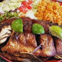 Mojarras · Whole deep fried tilapia fish simmered in lime-garlic juice served with Mexican salad and Me...