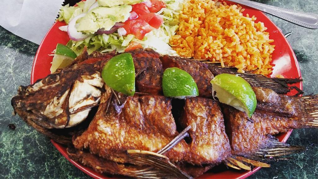 Mojarras · Whole deep fried tilapia fish simmered in lime-garlic juice served with Mexican salad and Mexican rice.