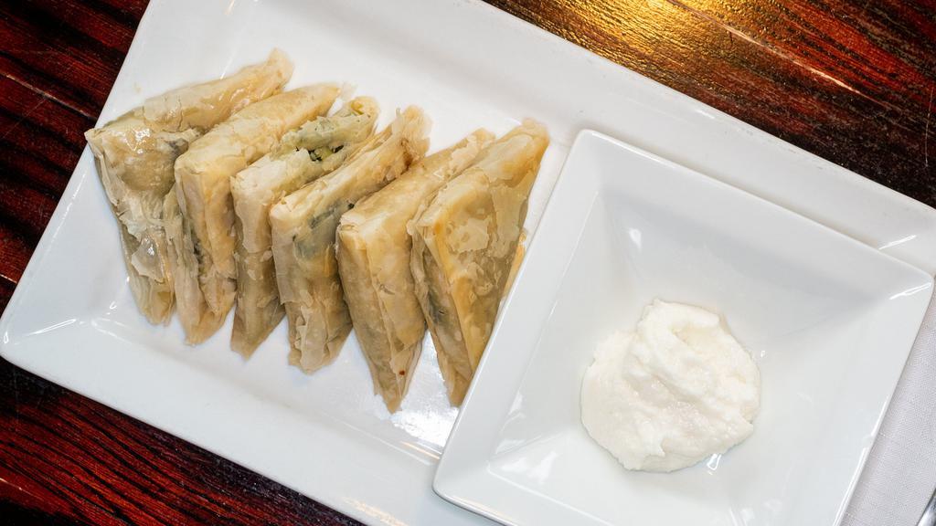 Spanakopita, Spinach Pies (Vegetarian) · Fresh tender spinach, feta cheese and herbs baked between flaky layers of fillo dough.  5 pieces served with lemon garlic dip.