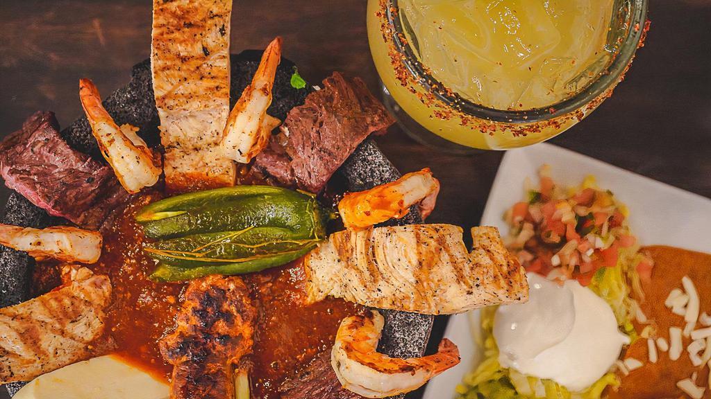 Molcajete Hacienda · Grilled chicken, sirloin steak, shrimp, chorizo, cactus, chambray onions, jalapeños, and queso fresco, topped with our chef's signature hot sauce. Served with rice and beans, lettuce, guacamole, sour cream, and pico de Gallo.