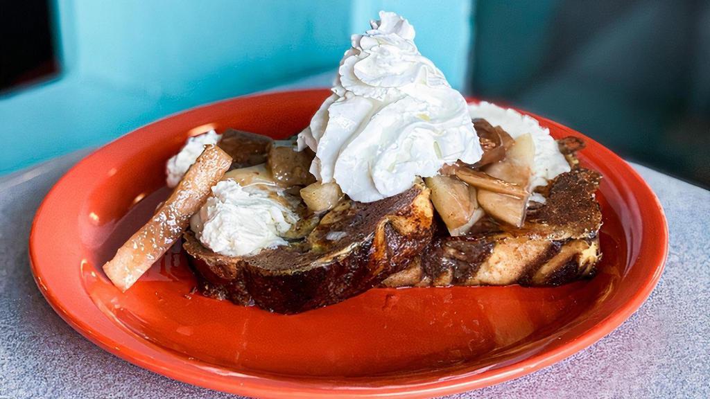 Cinnamon Roll French Toast Sweets · Two slices of grilled cinnamon french toast topped with seasonal fruit, buttercream icing, whipped cream, powdered sugar and served with maple syrup.