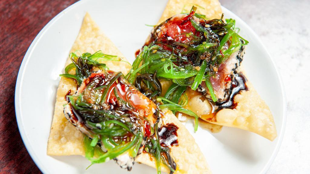 Ahi Tuna Nachos · Sashimi grade tuna on a bed of crispy fried wontons topped with a seaweed salad and drizzled with a balsamic reduction and a sweet chili sauce.