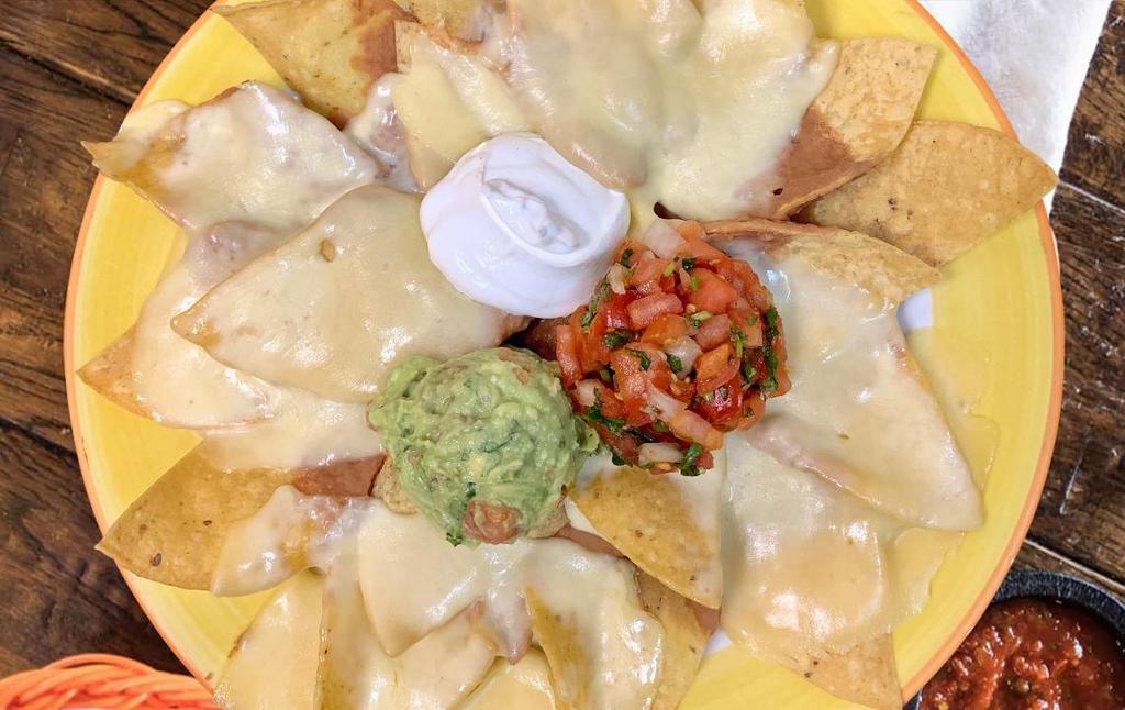 Nachos · Thick blend corn tortilla chips dipped in refried beans and topped with a layer of chihuahua cheese. Also served with pico de gallo, sour cream, and fresh guacamole.