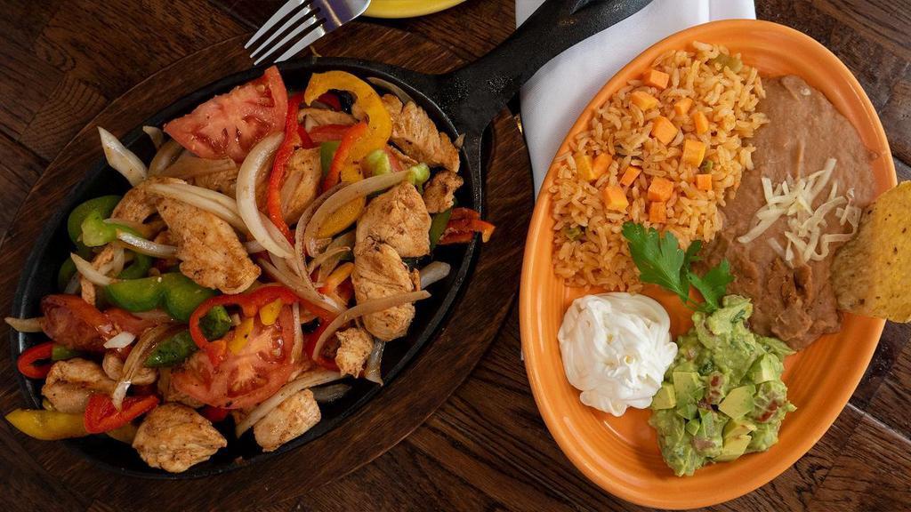 Fajitas De Pollo · Generous tender chicken breast, grilled with slices of onions, tomatoes, and colorful bell peppers. Served with a side of guacamole, sour cream, Spanish rice, refried beans and your choice of tortillas.