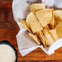 Chips & Chile Con Queso · Chips served with a white queso with fire-roasted chiles and tomatoes
