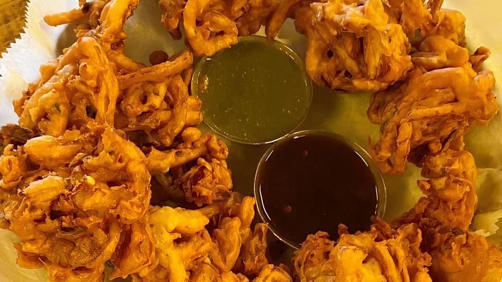 Pakoras · VEGAN - Sliced onions and cilantro mixed in a batter then fried into crispy puffs. All topped with dry masala, includes green chutney and tamarind chutney.
