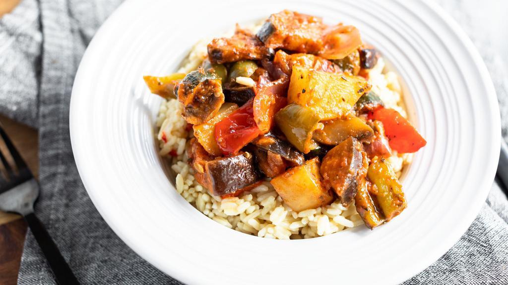 Vegetable Briami · crispy potatoes, red and green peppers, eggplant, zucchini, onion and tomato roasted in olive oil served over rice pilaf with salad