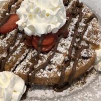 Nutty Pecan Waffle · Smothered in powdered sugar and drizzled with Nutella, and garnished with fresh strawberries.