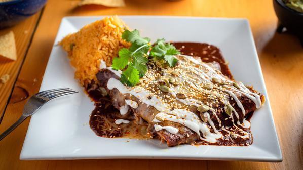 Enmoladas · Three rolled corn tortillas stuffed with Chicken, doused with our most famous red Mole sauce and served with Mexican Rice