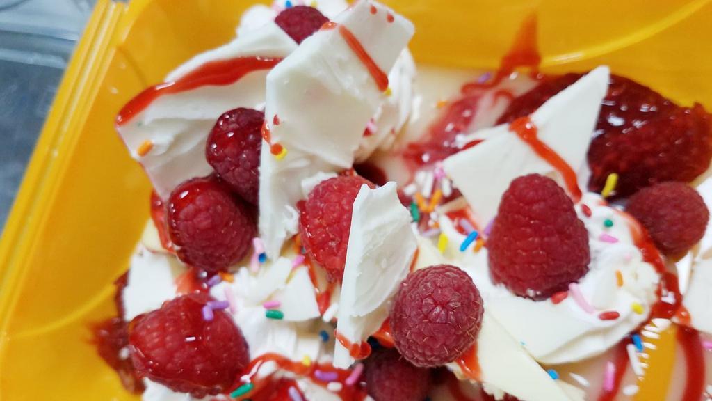 White Chocolate Raspberry Cheesecake Sundae · Fresh raspberries, raspberry compote, white chocolate and raspberry sauces with chunks of white chocolate and whipped cream topping.