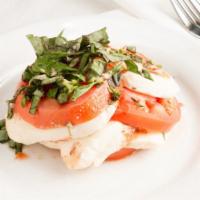 Caprese Salad · Stacked red tomatoes and mozzarella slices garnished with fresh basil, drizzled with olive o...