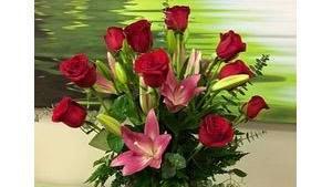 Isn'T It Romantic · One dozen red roses and lilies with assorted greens and arranged in a glass vase. Beautiful!...