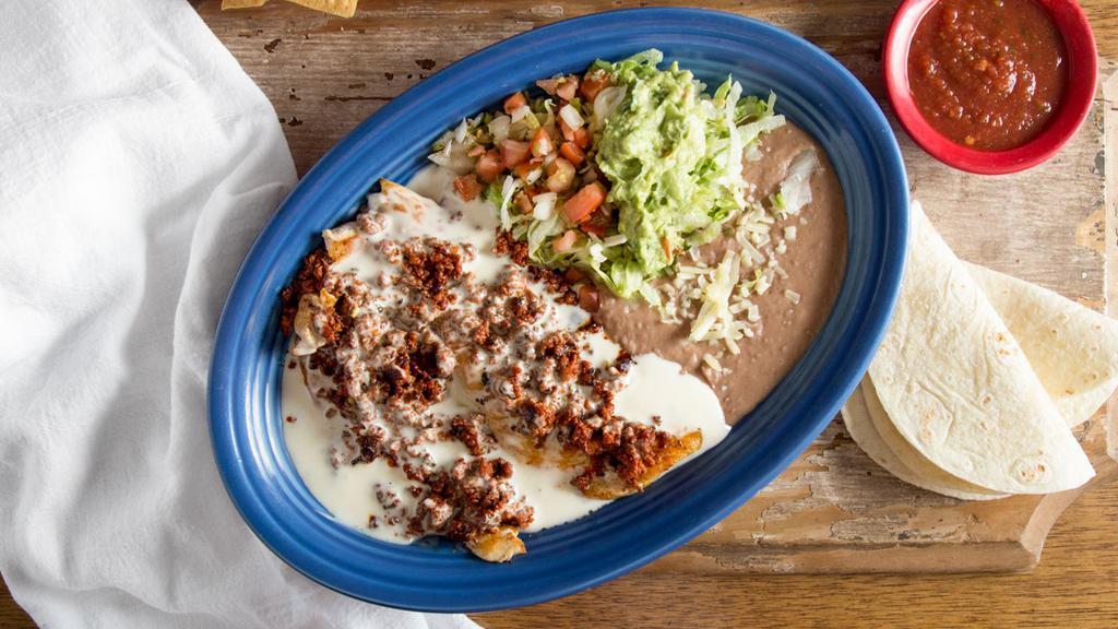 Pollo Michoacano · A grilled chicken breast topped with chorizo and cheese sauce and served with guacamole salad, beans, and tortillas.