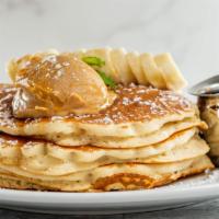 Canela Supreme Pancakes · Cinnamon pancakes layered with bananas and peanut butter drizzled with honey and topped with...