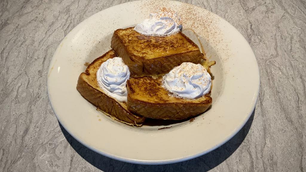 Cinnamon Caramel French Toast · Three slices of french toast served in a bowl with crumbled bacon topped with hot caramel and whipped cream dusted with cinnamon.
