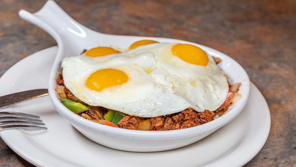 Chorizo Skillet · A skillet of hash browns with chorizo sausage, green peppers, onions, tomato, jalapenos, and Cheddar cheese, topped with two eggs any style served with toast.