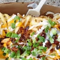 Smothered Waffle Fries · Waffle fries smothered in house-made queso, chopped bacon and green onion.