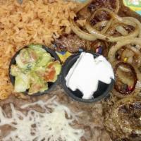 Bistec Encebollado · Steak topped with grilled onions.  Served with rice or fideo, refried beans and 3 corn torti...