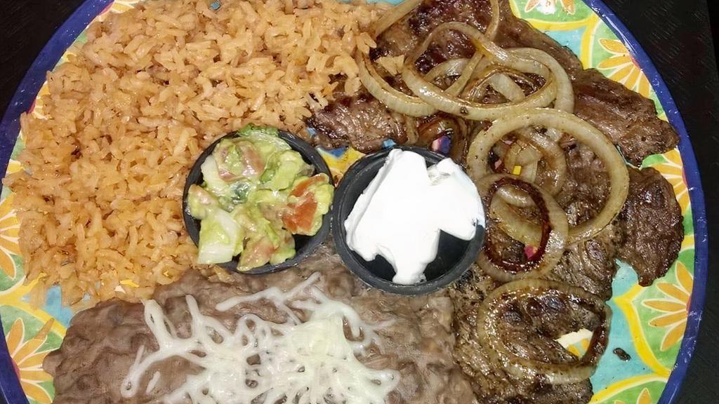 Bistec Encebollado · Steak topped with grilled onions.  Served with rice or fideo, refried beans and 3 corn tortillas.
