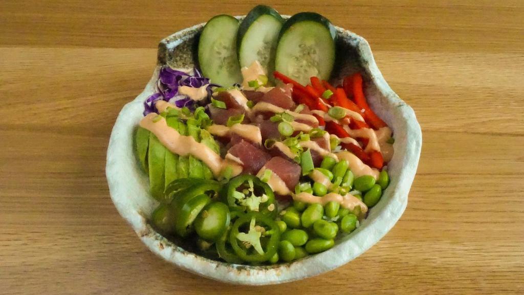 Volcano Poke Bowl · Sushi-grade ahi tuna* marinated in a lemongrass soy-ginger glaze, avocado, bell peppers, cucumber, red cabbage, jalapenos, and edamame on coconut rice topped with Sriracha aioli.