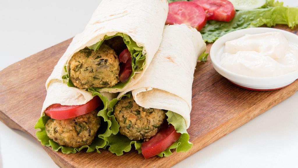 Falafel Sharek Wrap · Our homemade, crispy, fried falafel made with chickpeas and our blend of herbs and spices. Wrapped in freshly made sharek flatbread and topped with fresh tomatoes, onions, house pickles and tahini dressing.