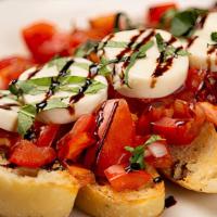 Bruschetta · marinated roma and sun-dried tomatoes topped with fresh housemade mozzarella served over foc...