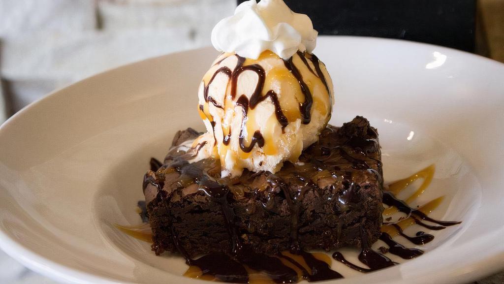 Brownie A La Mode · Warm, fudgy brownie topped with vanilla ice cream, chocolate, and caramel sauce and whipped cream.