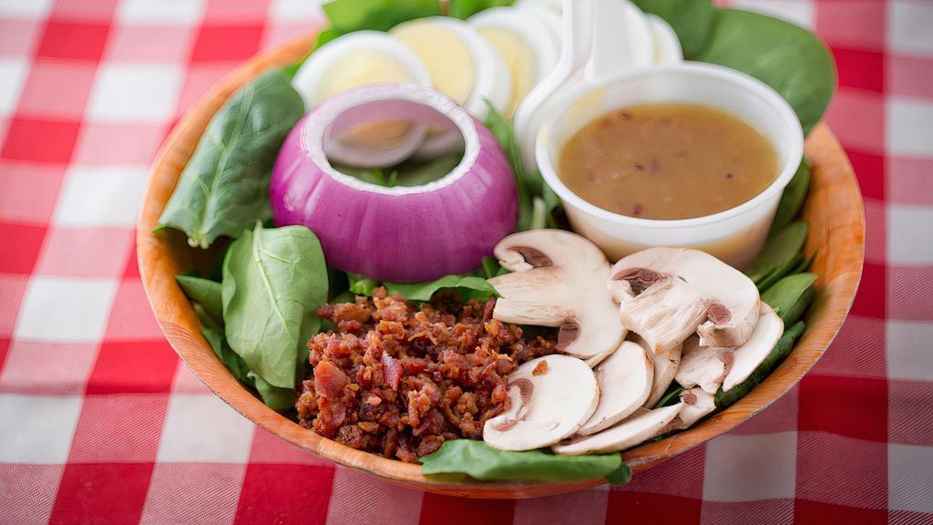 Spinach Salad · Fresh spinach topped with egg, mushroom, and red onion, served with a side of bacon bits and hot honey-bacon dressing.