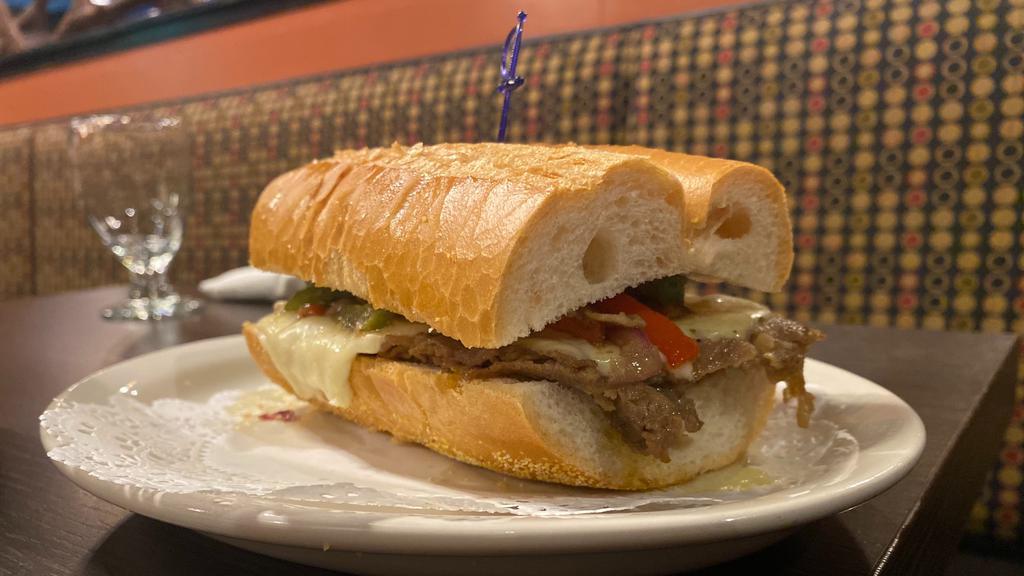 K’Bolá Philly Cheesesteak · Our k'Bola Philly cheesesteak is a sandwich made with super thinly sliced ribeye steak, red onions, Swiss cheese and bell peppers served on a Cuban bread.