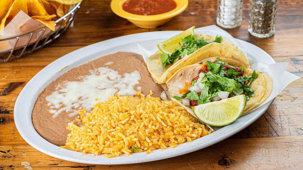 Tacos Al Pastor Plate · Marinated pork in a chili and onion based sauce for 24 hours then grilled with pineapple to create a sweet and hot experience. Served in corn tortillas and topped with onions, cilantro, and freshly squeezed lime. Rice and beans on the side.