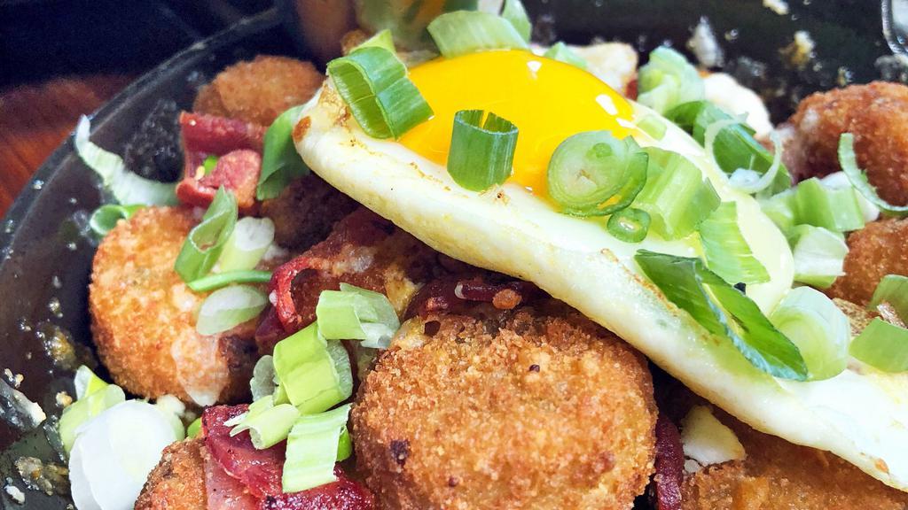 Loaded Rocket Tots · Jalapeño Potato Tots topped with Cheddar Jack Cheese, Goat Cheese, Bacon, Green Onions, and a Fried Egg. Served with Chipotle Sour Cream.