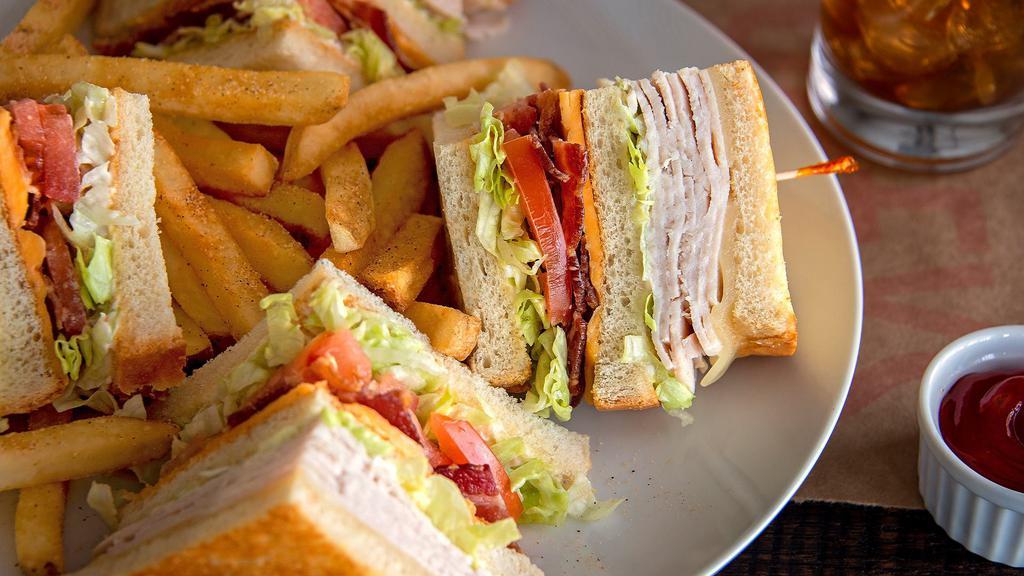 Turkey Club Sandwich · Slow-roasted turkey breast, hickory-smoked bacon, American and Swiss cheeses on grilled sourdough bread with lettuce, tomatoes, and mayonnaise. Served with French fries.