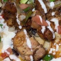 Jerk Chicken Nachos · Crispy tortilla chips layered with house queso, black beans, corn, jerk spiced chicken, fres...