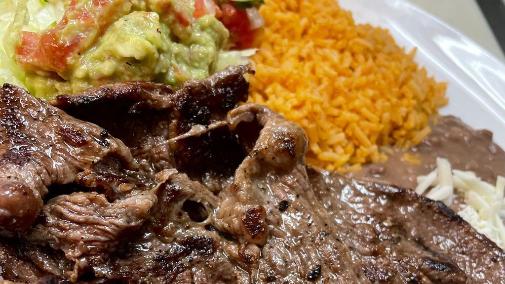 #15 Carne Asada Plate · Two Thin Slices Of Steak Comes With Rice & guacamole salad consisting of guacamole and pico on a bed of lettuce . Includes an order of tortillas
