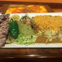 Carne Asada · Steak with re-fried beans, guacamole salad, flour tortilla and spanish rice.