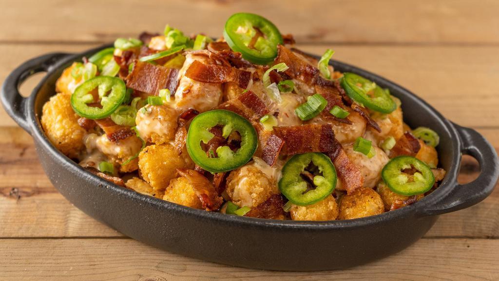 Loaded Tots · seasoned tater tots covered in warm queso, fresh jalapeños, applewood smoked bacon, scallions