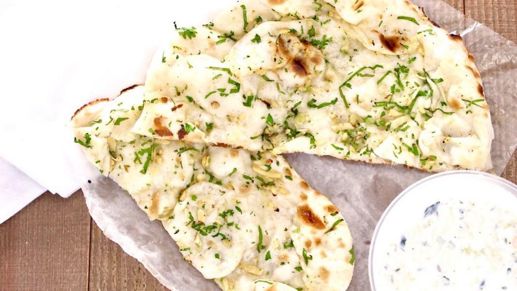 Garlic Naan · Naan Bread Topped With Pressed Garlic & Fresh Herbs.